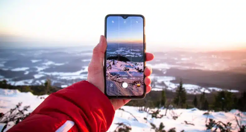 Pessoa segurando o celular para tirar foto e na República Tcheca durante o dia. Representa chip celular República Tcheca.