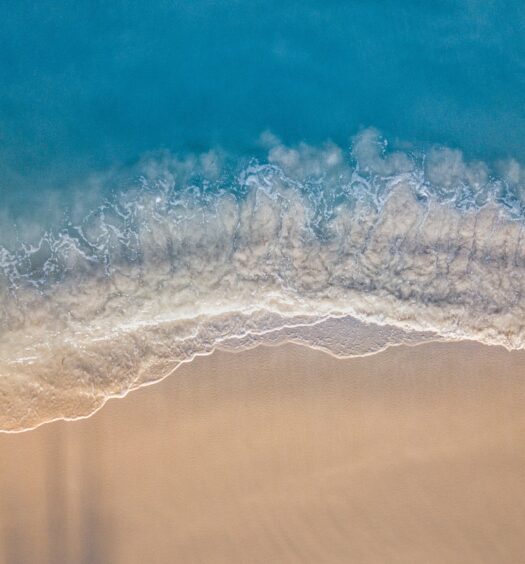 Mar azul turquesa, ondas quebrando com espuma branca, e areia dourada em praia de Aruba, ilustrando o post de chip de celular para Aruba