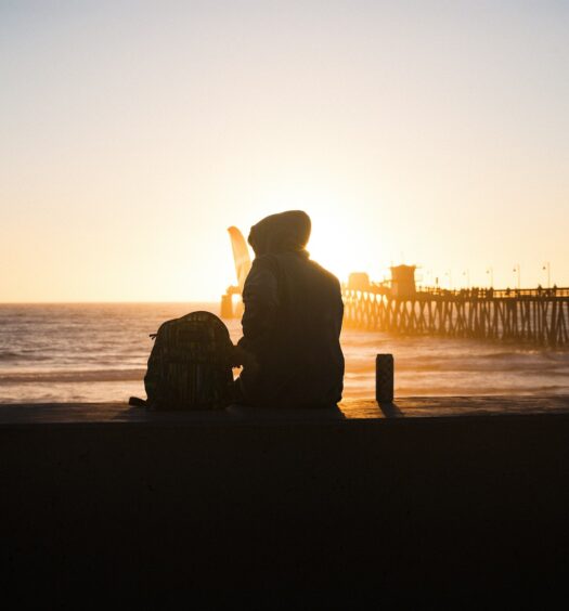 Pessoa sentada em frente ao pôr do sol da praia de San Diego, ilustrando post chip celular San Diego.