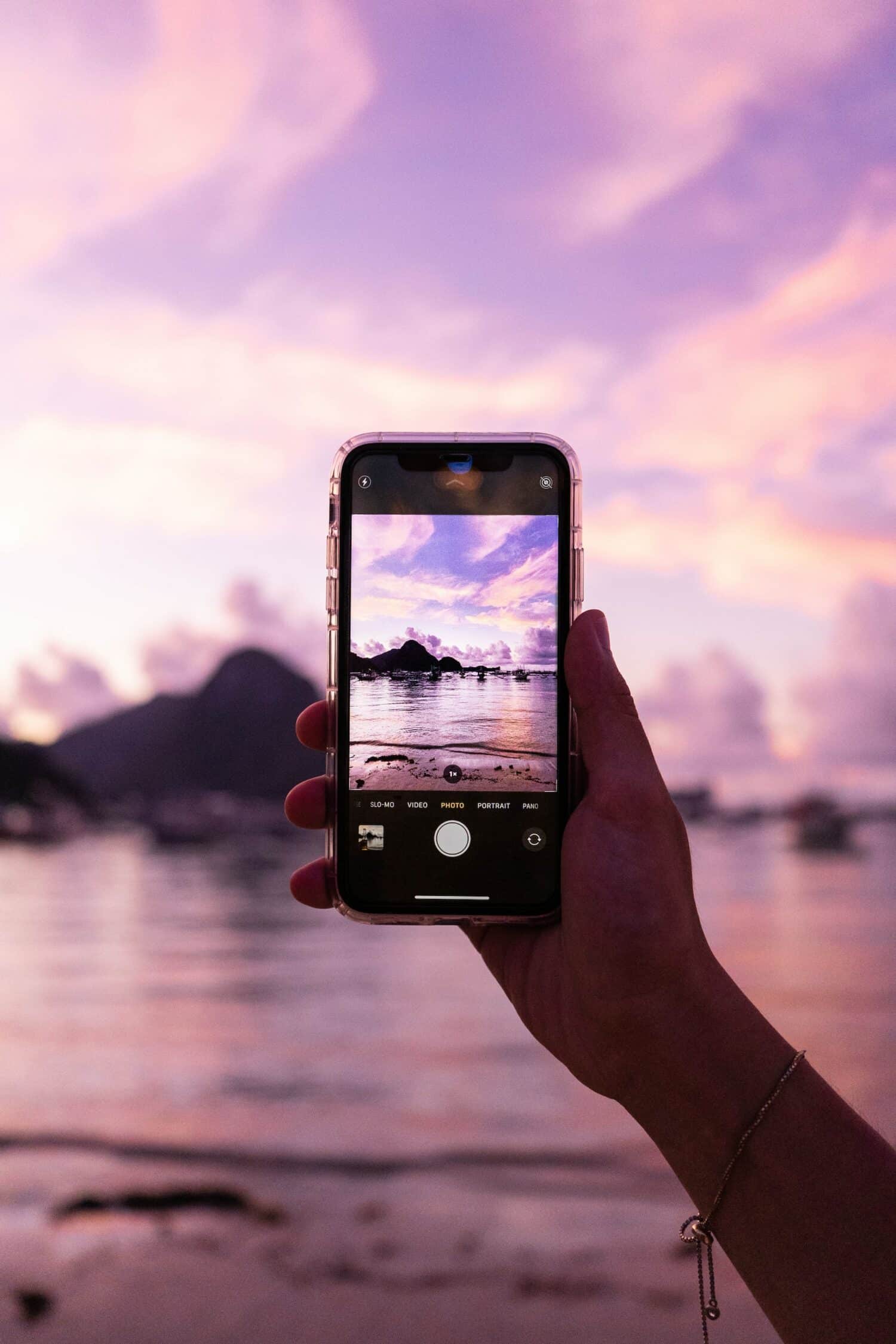 Mão segurando um celular tirando foto da praia El Nido, nas Filipinas. Imagem para ilustrar o post chip de celular Filipinas