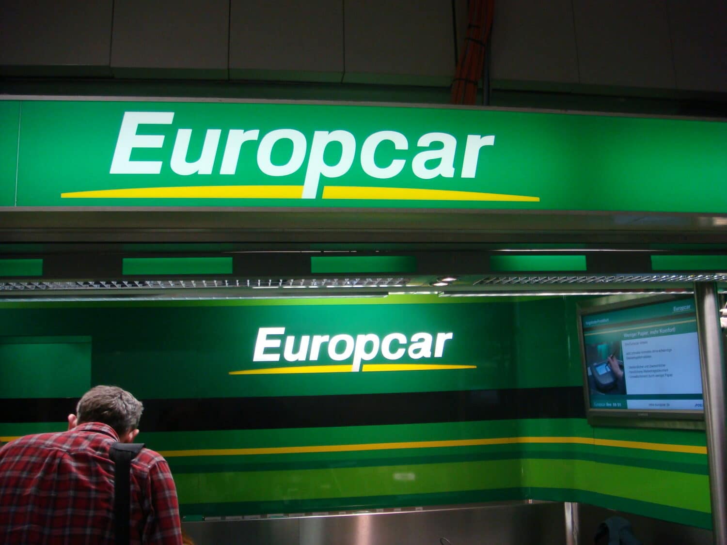 Logos da Europcar, com fundo verde, letras brancas e sublinhado amarelo, ilustrando o post sobre a locadora Europcar Rent a Car