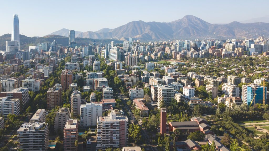 Vista aérea de Santiago, as ruas são cercadas por muitas árvores, não há tantos prédios comerciais, e ao fundo, você consegue ver a cordilheira
