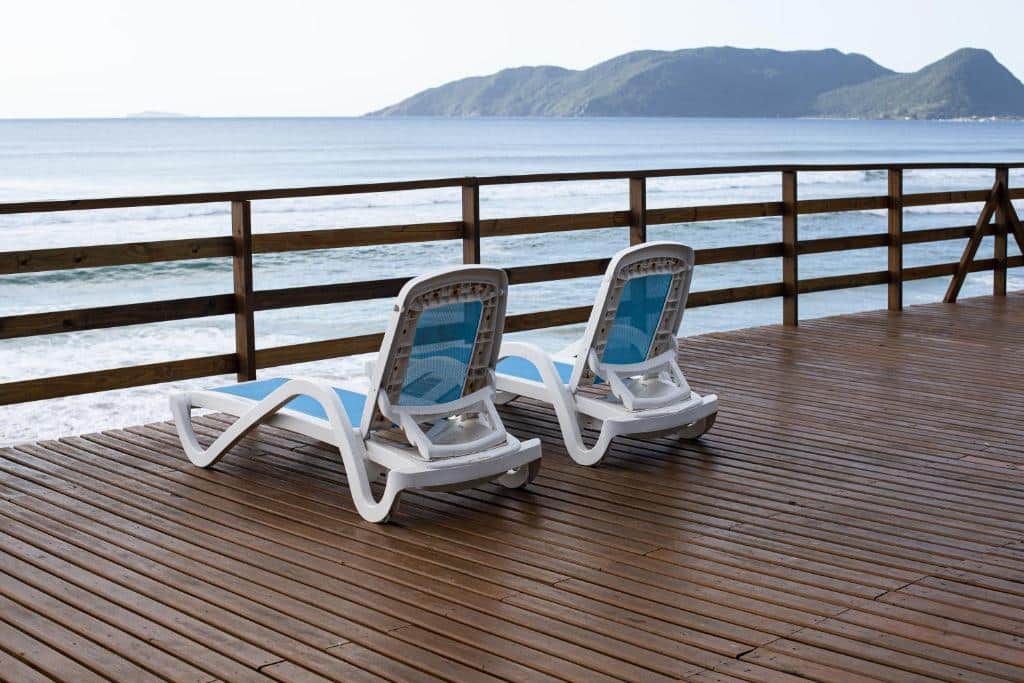 Duas espreguiçadeiras simples em um deck de madeira com vista direta para a praia no Hibisco Guest House
