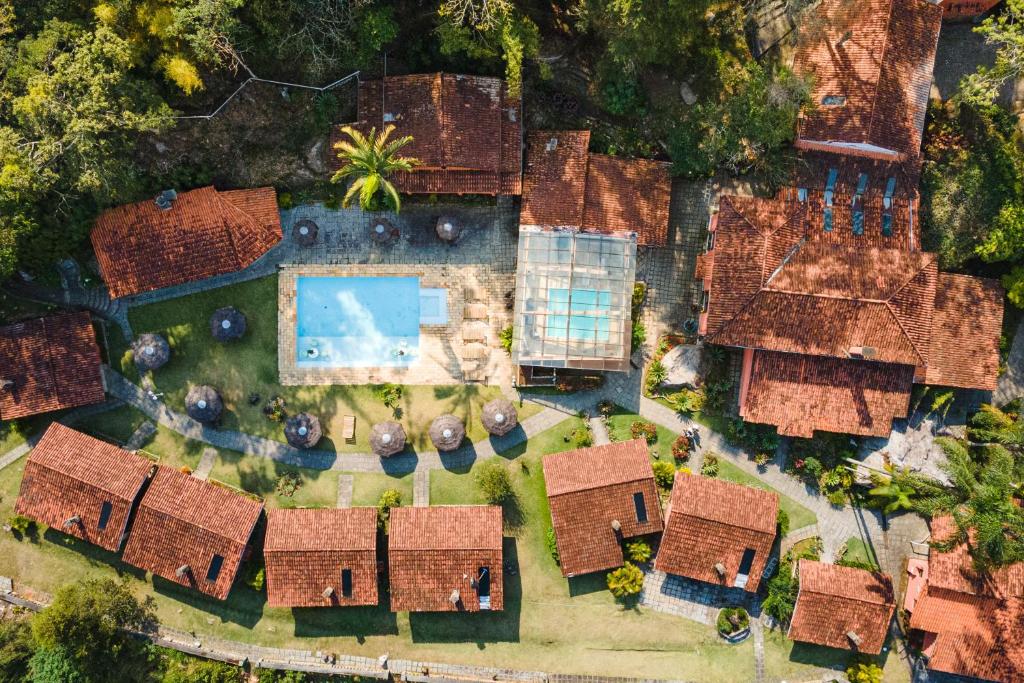 Vista aérea do Hotel Pedra Bonita com uma piscina ao ar livre e outra coberta, com gramado ao redor e alguns guarda-sóis