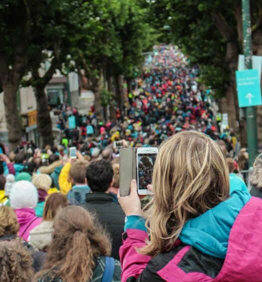 Mulher apontando o celular para uma multidão na Irlanda para representar o chip celular Irlanda