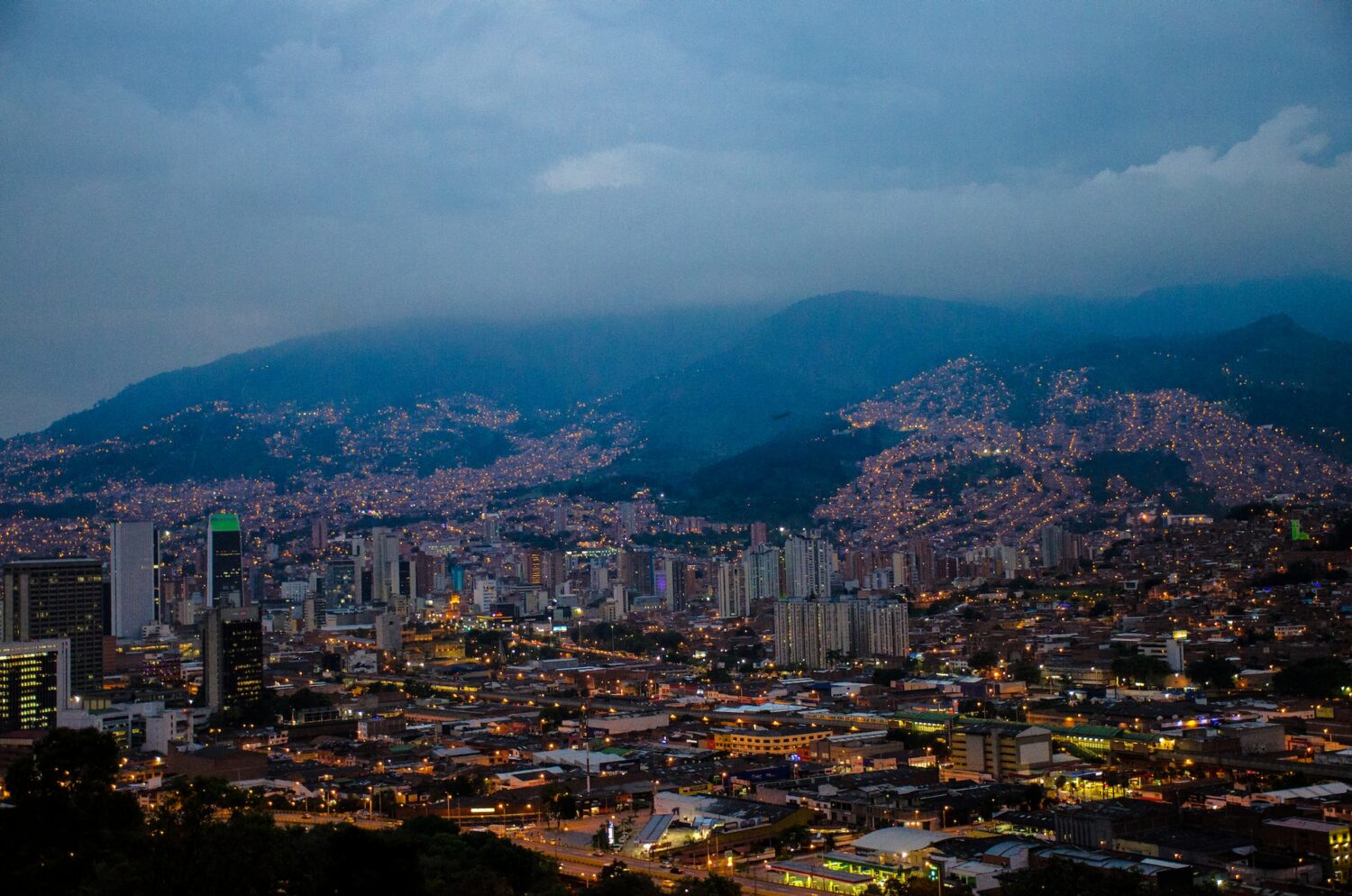 Vista da cidade com poucos prédios, algumas luzes acesas e muitas montanhas ao fundo, para representar chip celular Medelin