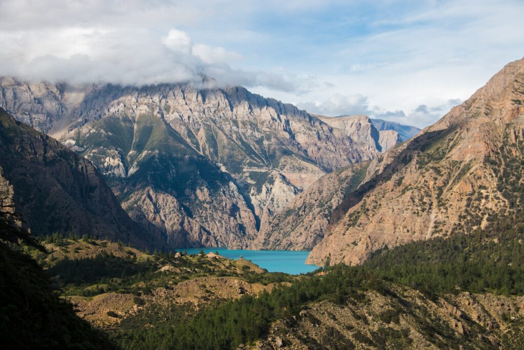 Montanhas, no Nepal, com o lago Phoksundo ao meio. A água do lago é azul turquesa e há bastante vegetação nas redondezas