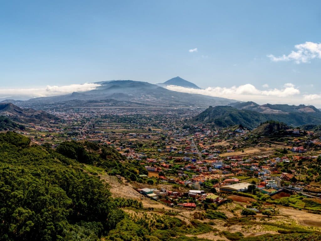Vista de um mirante da região de Las Mercedes, em Caracas, com uma montanha com bastante vegetação e várias casas abaixo, além de montanhas no horizonte