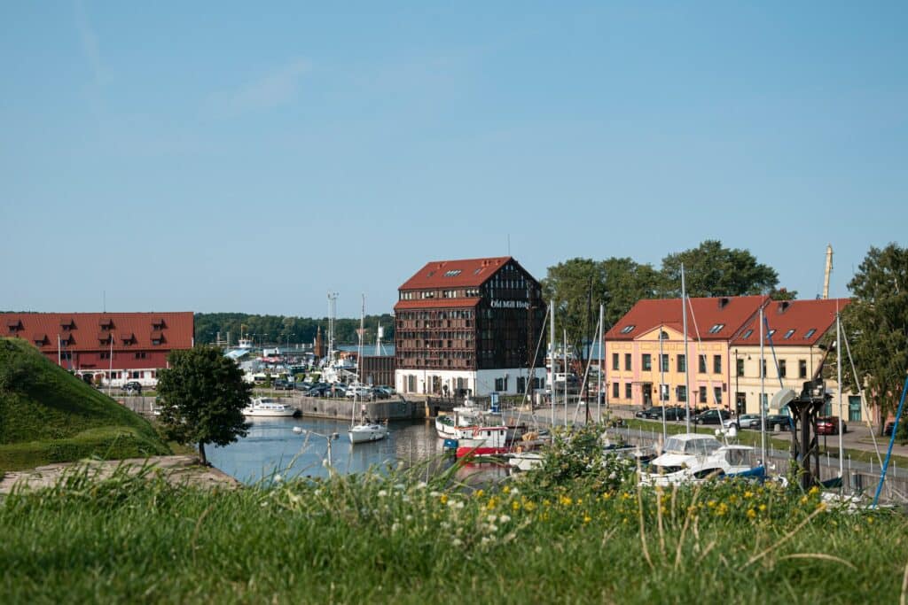 Kaipleda na Lituânia, casas com um rio ao centro, algumas embarcações e ao entorno vegetação.