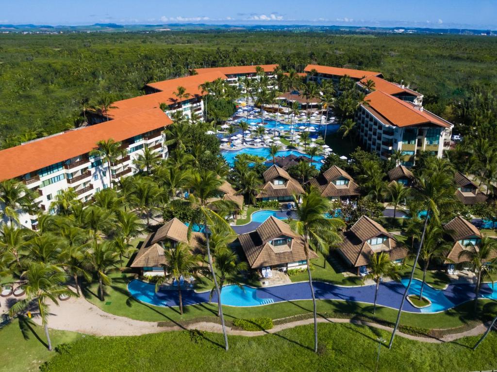 Vista aérea do Marulhos Suítes Resort by MAI com muitas piscinas, diversas palmeiras, a propriedade é rodeada de árvores