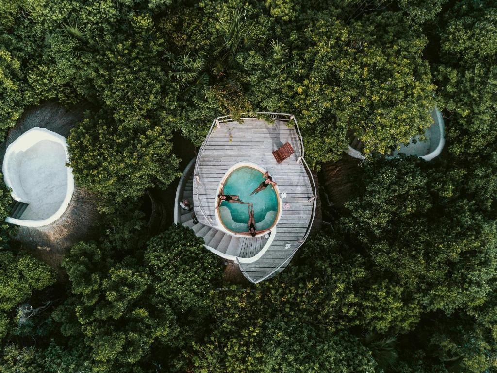 Vista aérea da cobertura de uma acomodação do hotel Papaya Playa Project, em Tulum, que tem uma piscina redonda e bastantes árvores verdes em volta