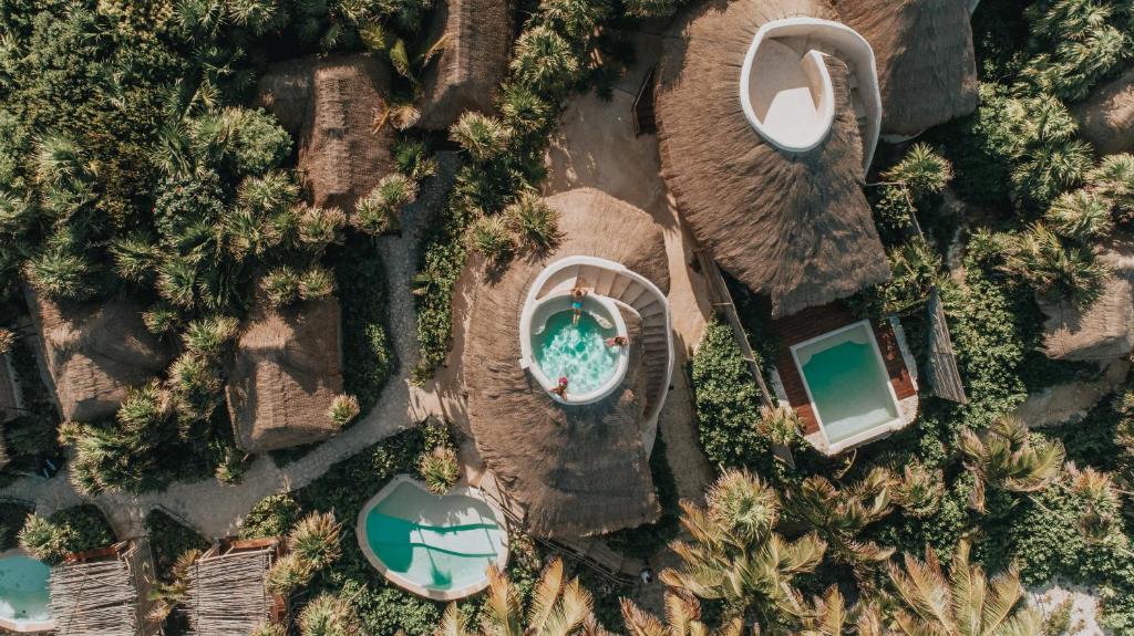 Vista aérea do hotel Papaya Playa Project, em Tulum, mostrando o teto das acomodações que ficam no meio da natureza, com piscina na cobertura
