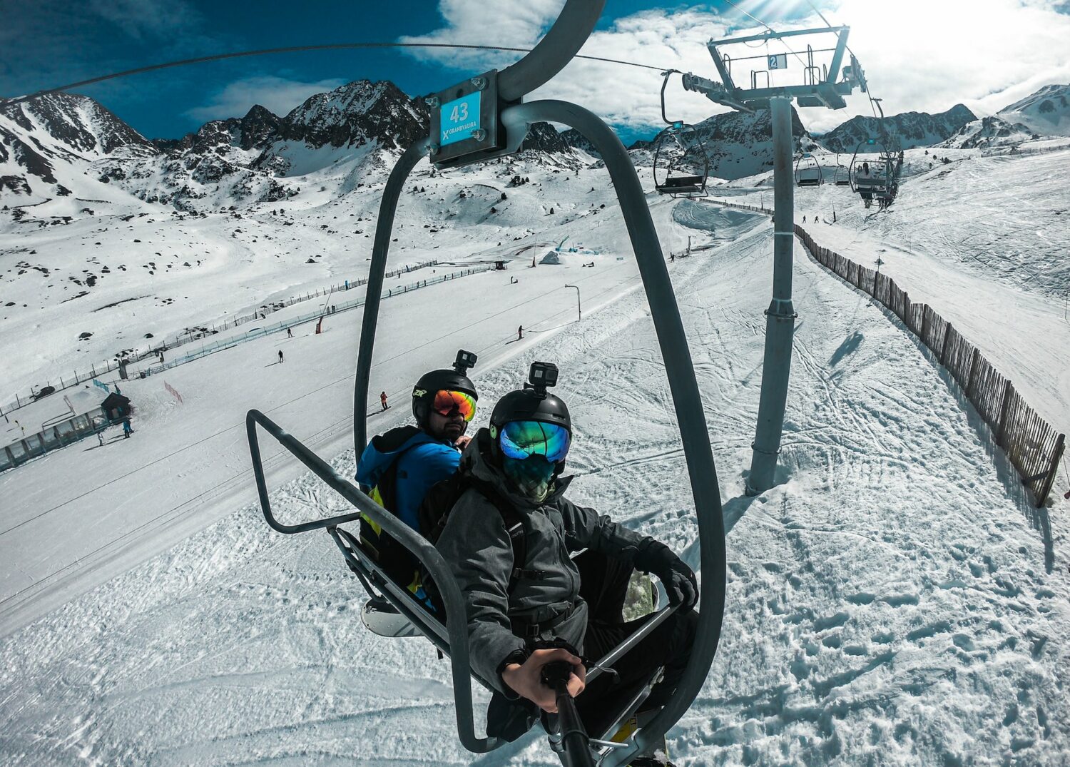 Duas pessoas andando em um teleférico ao redor de bastante neve em uma estação de esqui durante o dia, ilustrando post chip celular Andorra.