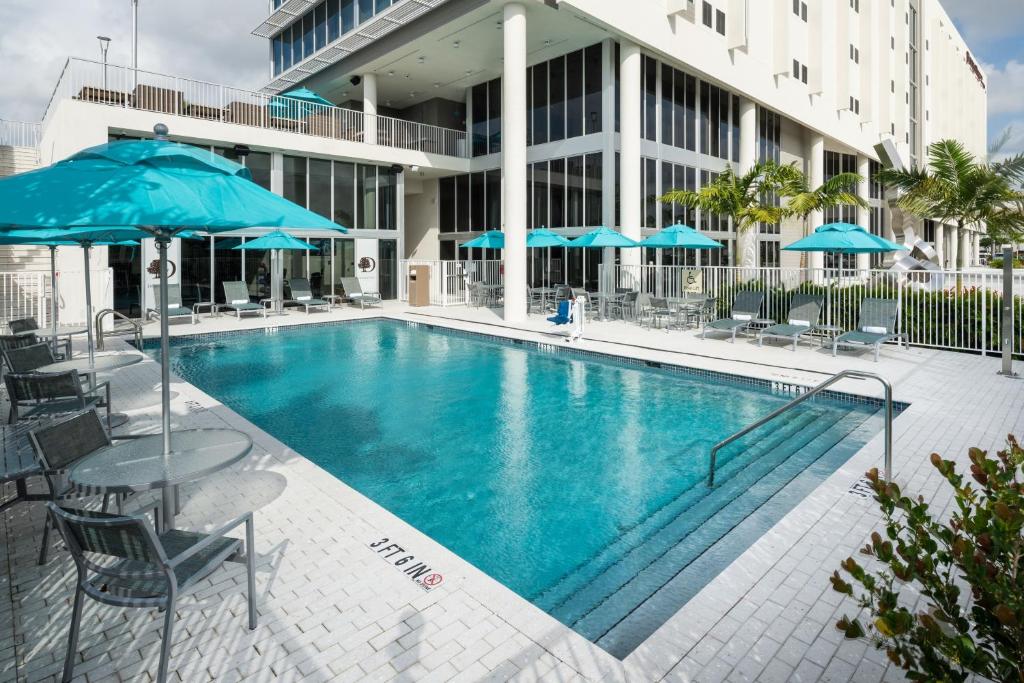 Vista da piscina do DoubleTree by Hilton durante o dia com cadeiras e guarda-sóis em volta da piscina. Representa hotéis em Miami.