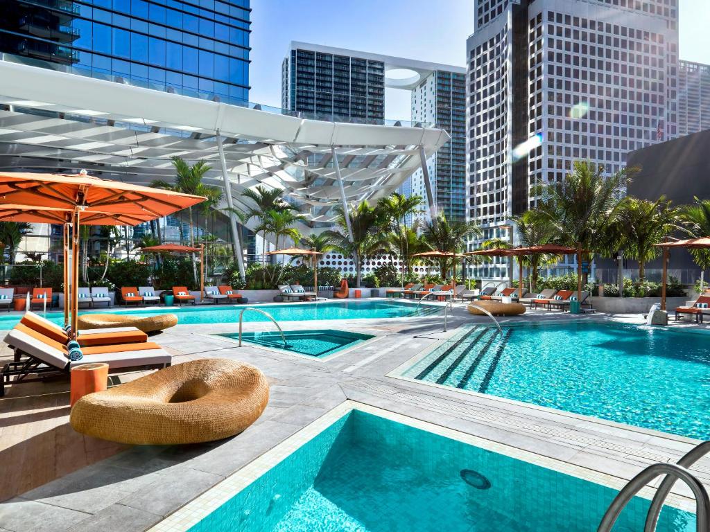 Vista da piscina do East Miami durante o dia, com cadeiras em volta da piscina e algumas árvores em volta. Representa Hotéis em Miami.