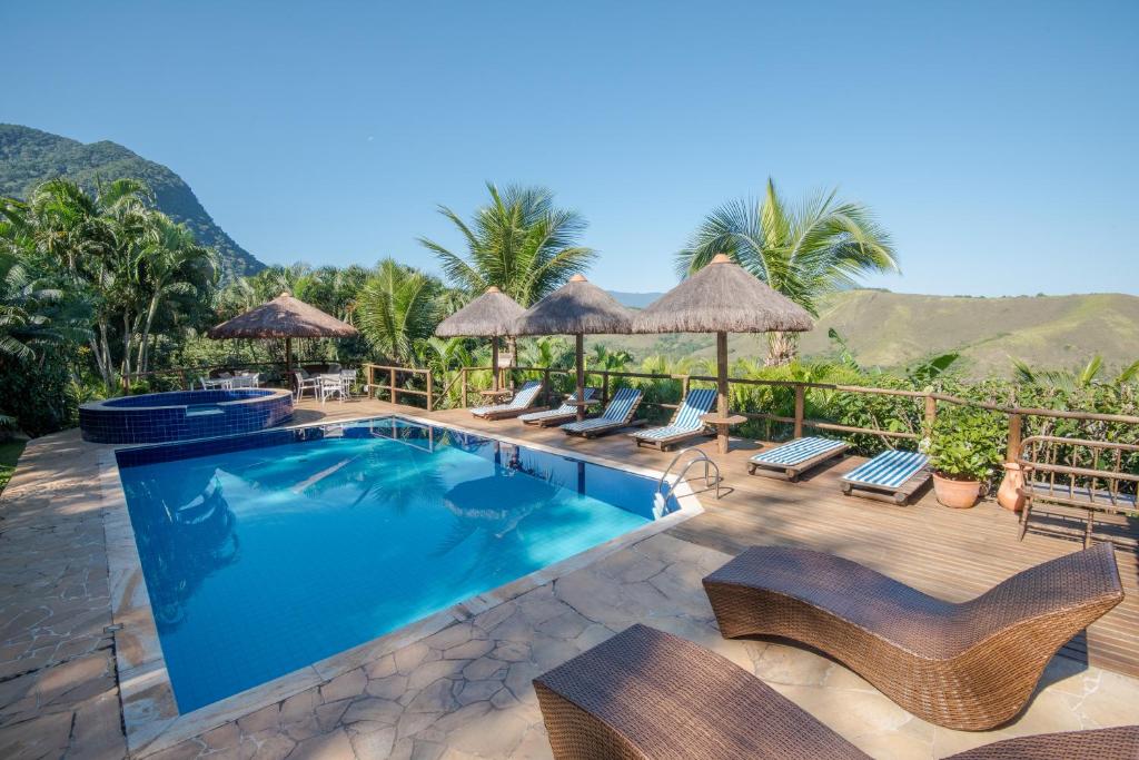 Vista da piscina da Ilha de Toque Toque Boutique Hotel & Spa durante do dia com cadeira em volta da piscina. Representa pousadas na praia de Calhetas.
