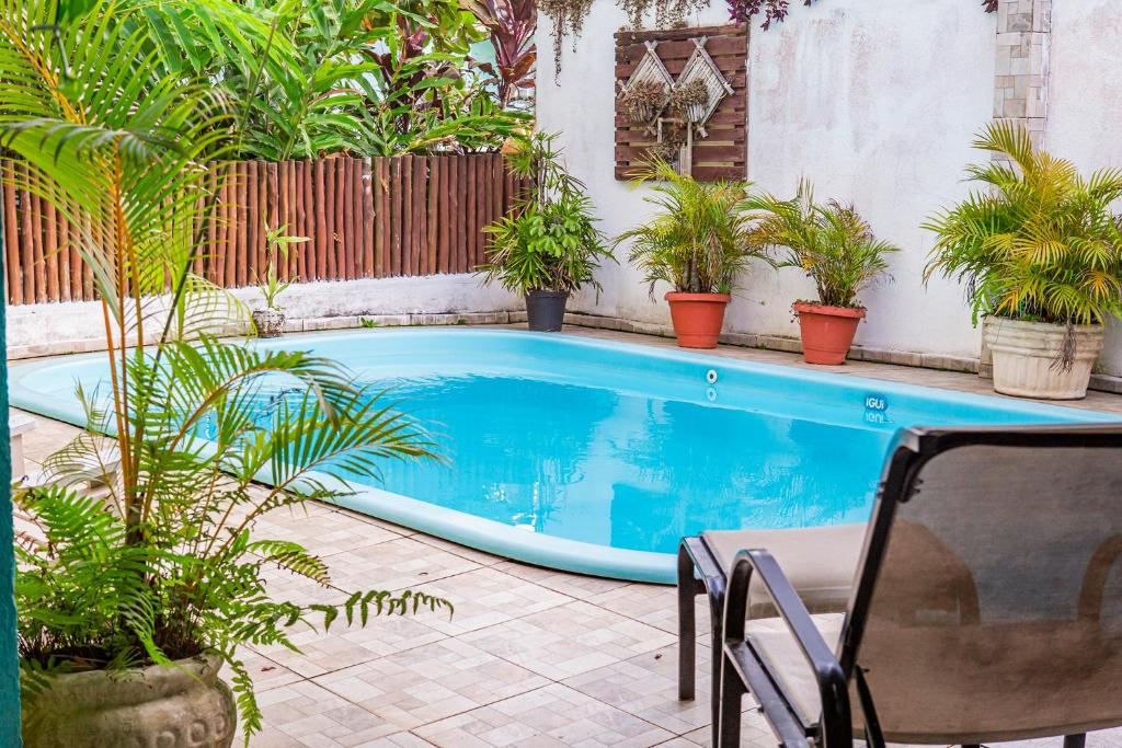 Vista da piscina da Pousada Castelinho durante o dia com cadeira do lado direito e do lado esquerdo vaso de plantas. Representa pousadas na praia de Guaecá.