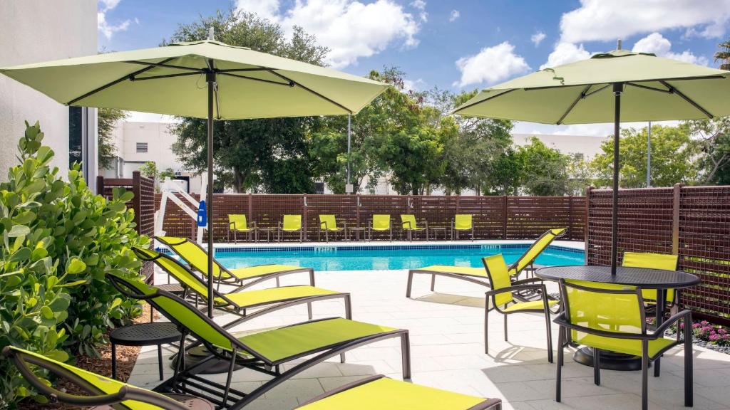 Vista da piscina do SpringHill Suites by Marriott durante o dia com cadeiras e guarda-sóis em volta da piscina. Representa hotéis em Miami.