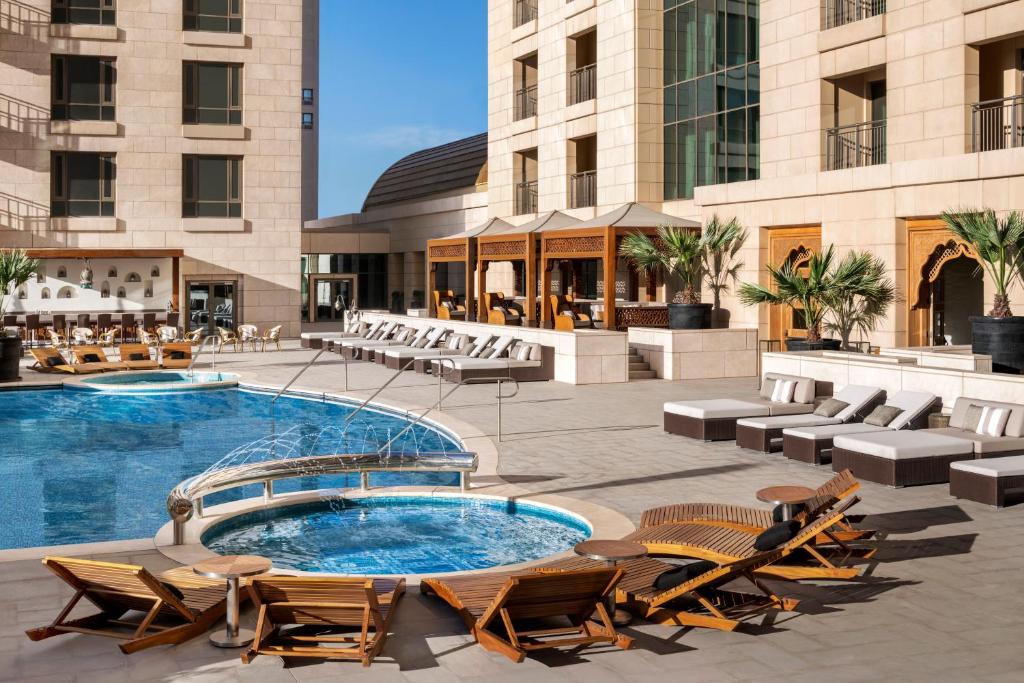 Vista da piscina do The St. Regis com cadeiras envolta da piscina durante o dia. Representa Hotéis no Cairo.