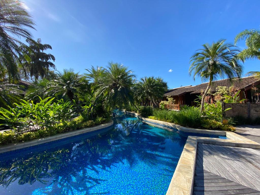 Vista da piscina do Villa Bebek Hotel durante o dia com árvores e plantas do lado esquerdo em volta da piscina.