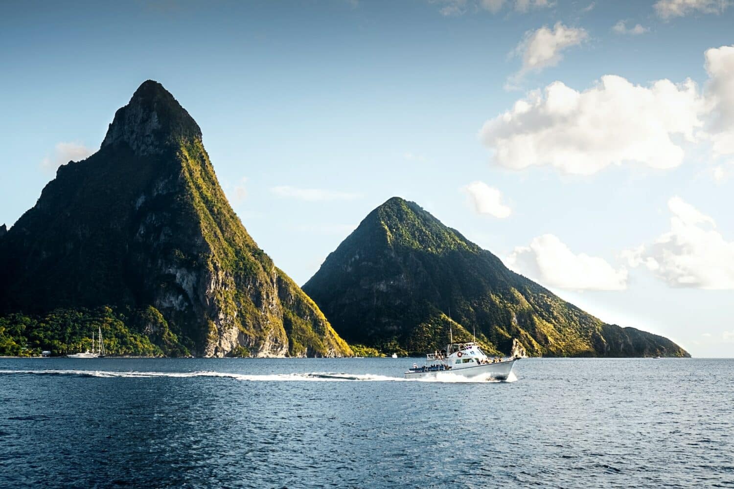 Barco branco no mar azul em frente aos picos vulcânicos chamados de "Gros Piton" durante o dia, ilustrando post chip celular Santa Lúcia.