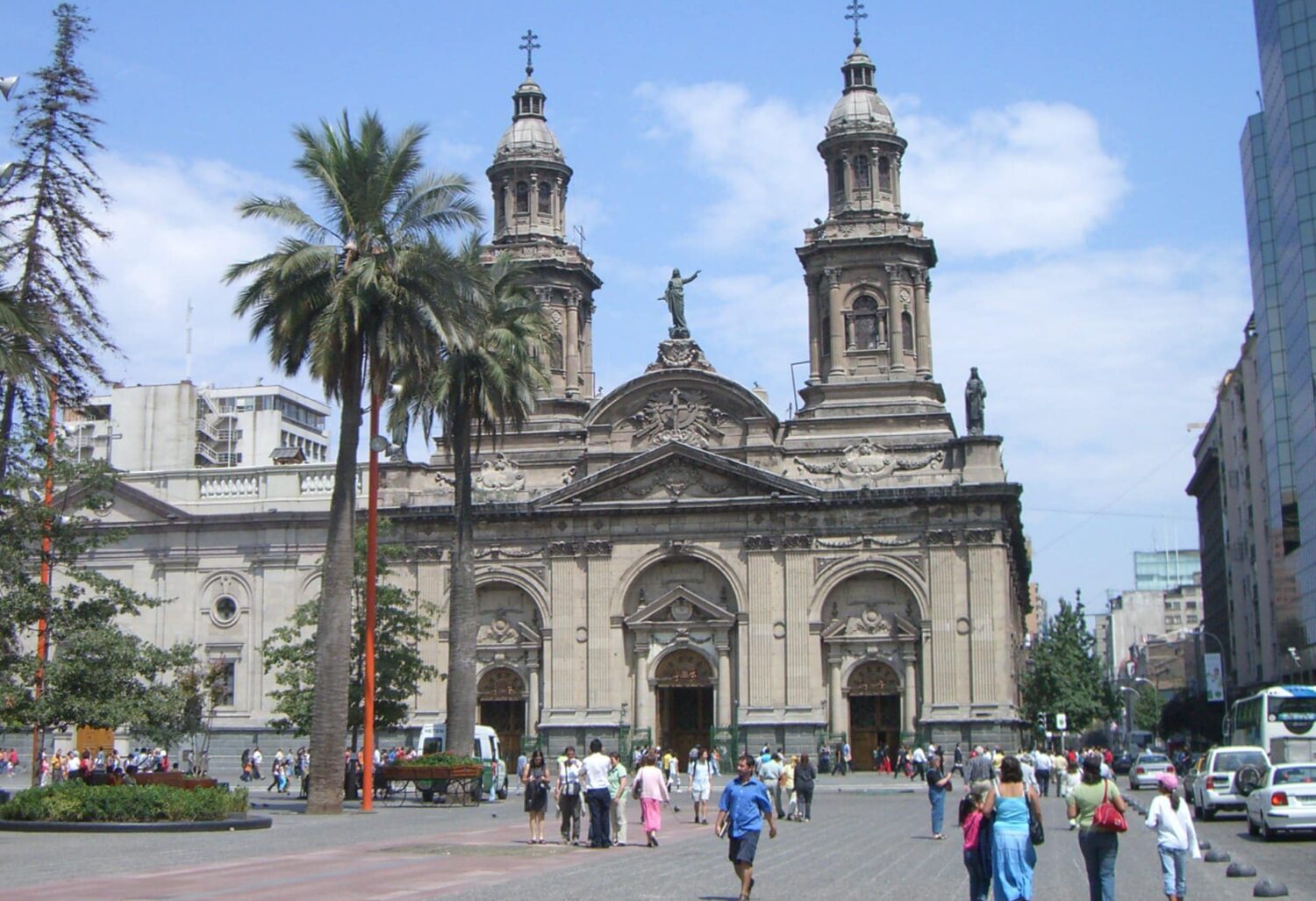 Vista da Plaza de Armas, em Santiago, Chile, durante o dia com prédio antigo a frente e algumas pessoas andando na praça. Representa Santiago.