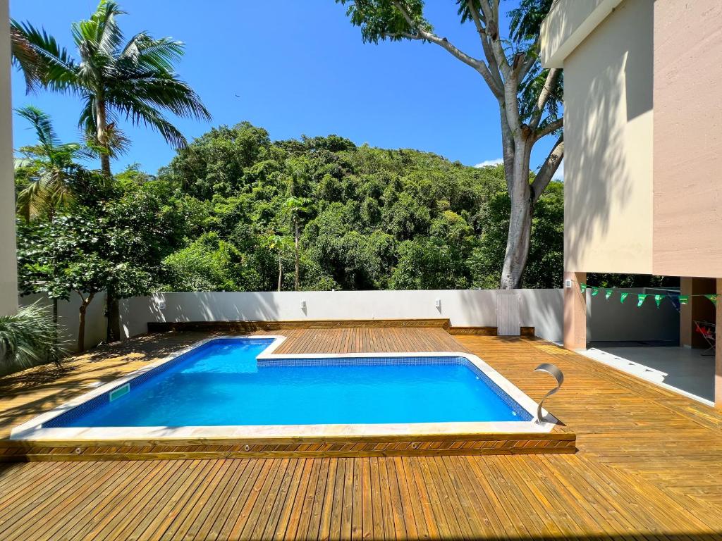 Deck da Pousada Altas Natureza com uma piscina e, ao redor da propriedade, muito verde e árvores por todo lado, para representar pousadas na Praia do Campeche