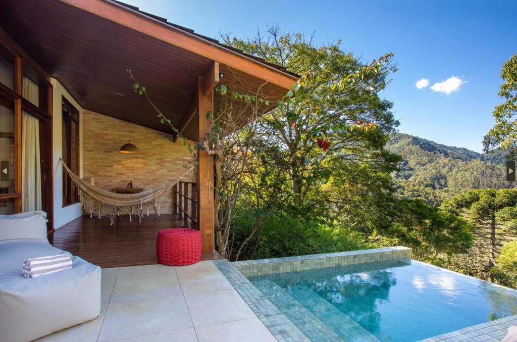 Varanda de um dos quartos da Pousada do Cedro com uma piscina privativa de frente para a natureza, com uma rede de descanso e um sofá com uma toalha em cima
