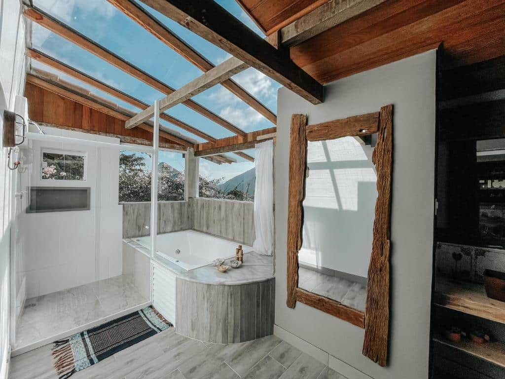 Banhheiro da Pousada Quinta das Nascentes com teto de vidro, banheira de hidromassagem, box de vidro e um espelho de corpo inteiro