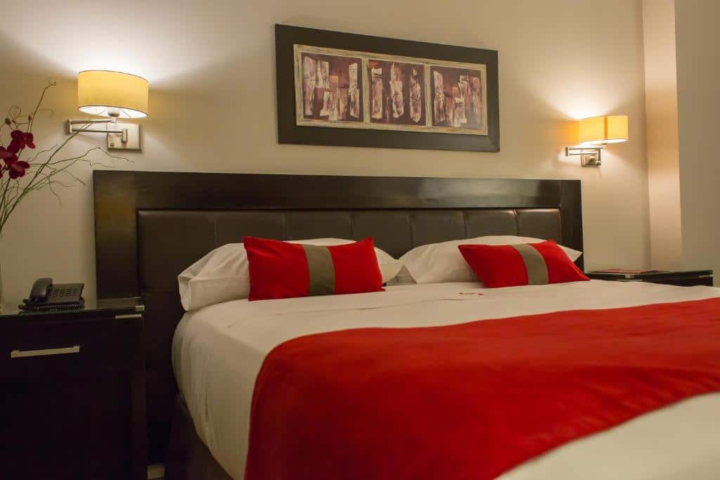 suíte do Alto Andino Hotel com uma cama de casal decorada com lençóis brancos e vermelhos
