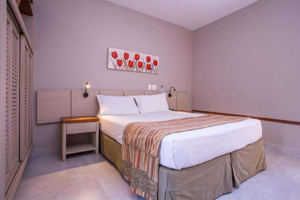 Quarto da Ciribaí Praia Hotel com cama de casal, duas cômodas de madeiras com luminárias.