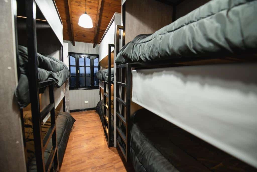 camas do quarto compartilhado do El Refugio Logde Hostel. Há quatro beliches do lado direito e uma beliche do lado esquerdo.