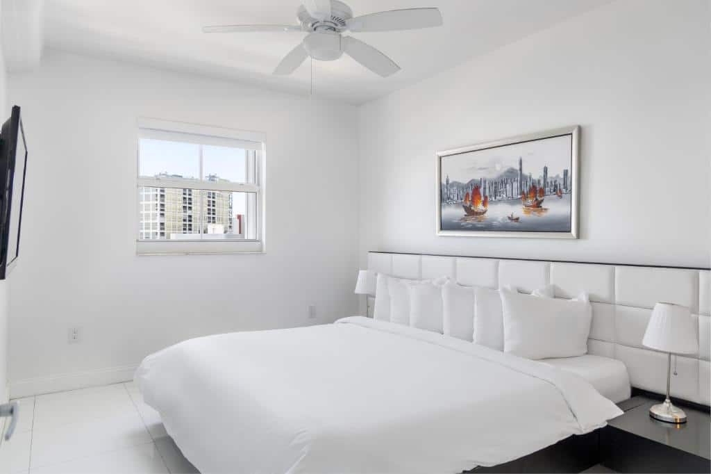 Quarto do Fortune House Hotel Suites  com cama de casal, quadro acima da cama, duas cômodas com luminárias e TV em frente a cama na parede.