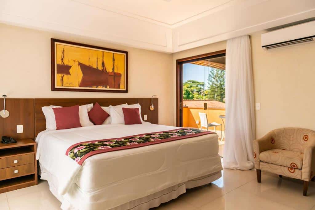 QUarto do Hotel Ferradura Resort com uma pequena sacada, uma cama de casal, um ar-condicionado de teto, uma poltrona e duas mesinhas de cabeceira
