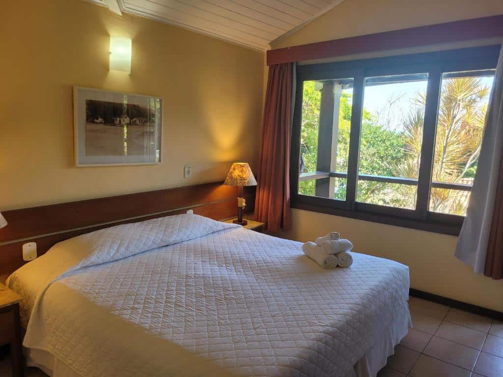 Quarto do Hotel La Forêt & Beach Club com uma cama de casal, uma janela ampla com cortinas e duas mesinhas de cabeceira com abajures