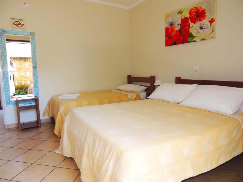 Quarto da Pousada Mosaico Brasil com cama de casal a frente e ao fundo cama de solteiro e um espelho grande na beira da cama.