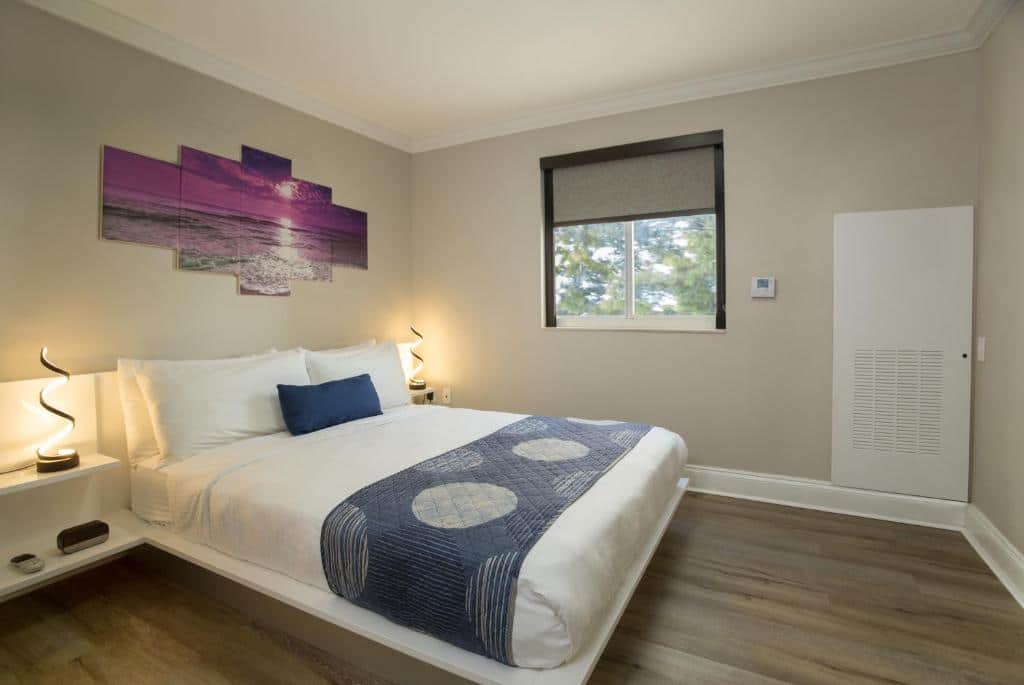 Quarto do Nuvo Suites Hotel – Miami / Doral com cama de casal, duas cômodas ao lado da cama com luminária.