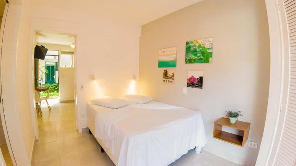 Quarto do Porto Paúba com cama de casal, cômoda de madeira abaixo da cama com vaso de flores.