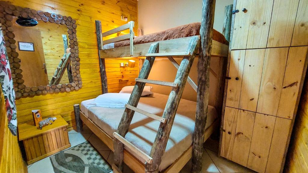 cama de casal com uma beliche de solteiro em cima, um armário de madeira ao lado direito e uma cômoda à esquerda na.