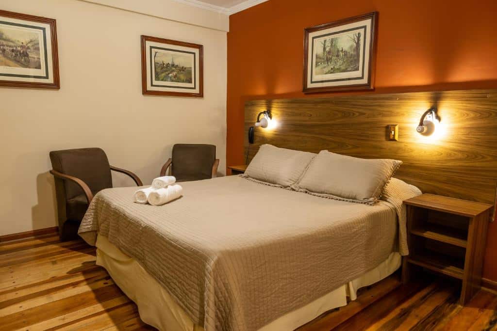 Quarto da Pousada Kaliman Premium com cama de casal, chão de madeira, duas poltronas e duas mesinhas de cabeceira com luminárias presas