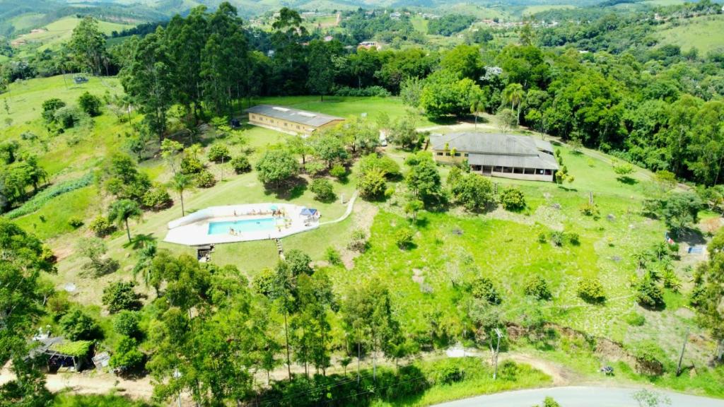 Vista aérea da pousada Recanto Varandas Guararema, com uma piscina, dois prédios e bastante natureza verde em volta