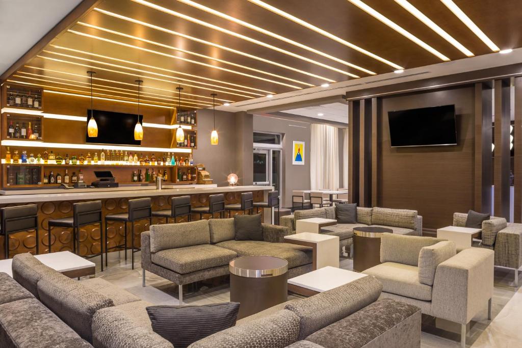 Recepção do Wingate by Wyndham Miami Airport com sofás e poltronas e ao fundo balcão com bar ao fundo. Representa hotéis em Miami.