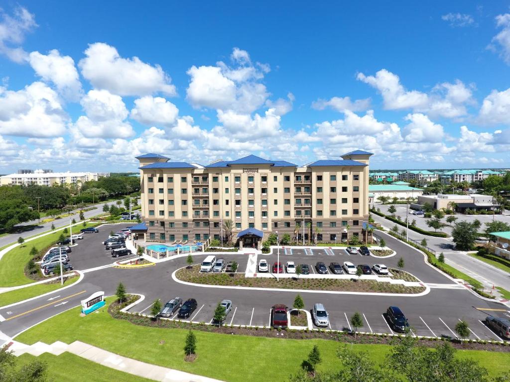 Prédio do Staybridge Suites Orlando at SeaWorld, an IHG Hotel com um amplo estacionamento a céu aberto ao redor da construção de cinco andares com telhados em tom de azul