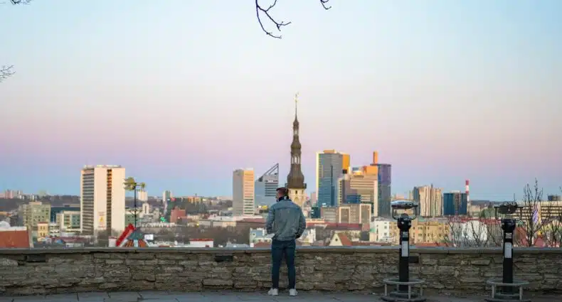 Homem olhando para a paisagem de Tallinn, com bastante construções durante o dia, ilustrando post chip celular Estônia.