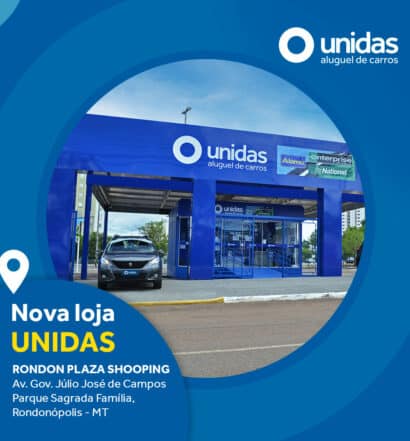 Nova loja Unidas Rent a Car em Rondonópolis (MT), com fachada azul e carro saindo do estacionamento da locadora, em dia de céu claro e com rua vazia à frente