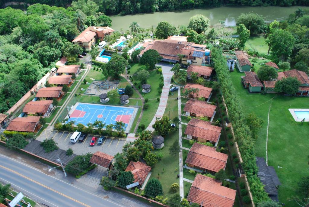 Vista aérea do Vale do Sonho Hotel, uma das opções de pousadas em Guararema, com teto de vários chalés um ao lado do outro, quadra de tênis, piscina e bastante natureza em volta