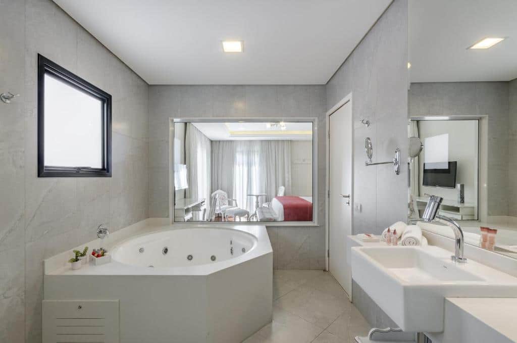 Banheira da Villa D’Biagy Premium com uma banheira de hidro, uma pia, uma janela transparente com vista para o quarto