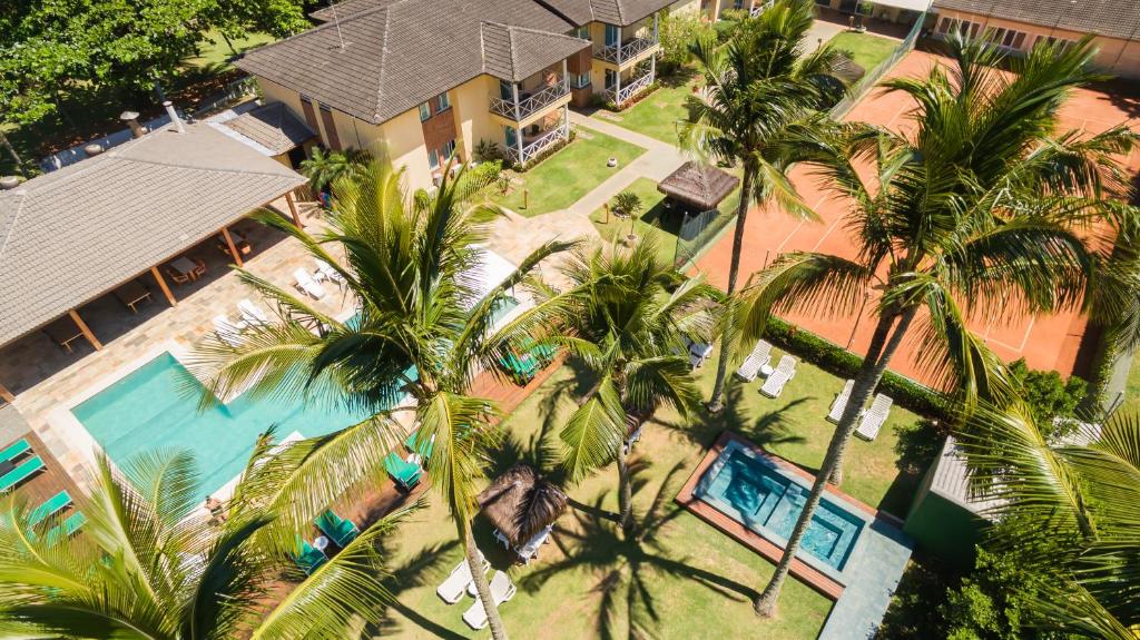 Vista de cima da Vistabela Resort & Spa durante o dia com a hospedagem, piscina e coqueiros. Representa pousadas na praia de Guaecá.