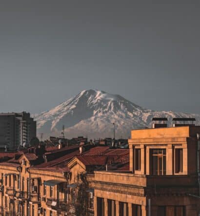 Imagem de edifícios em tons de marrom e ao fundo uma montanha com neve, ilustrando post chip celular Armênia.
