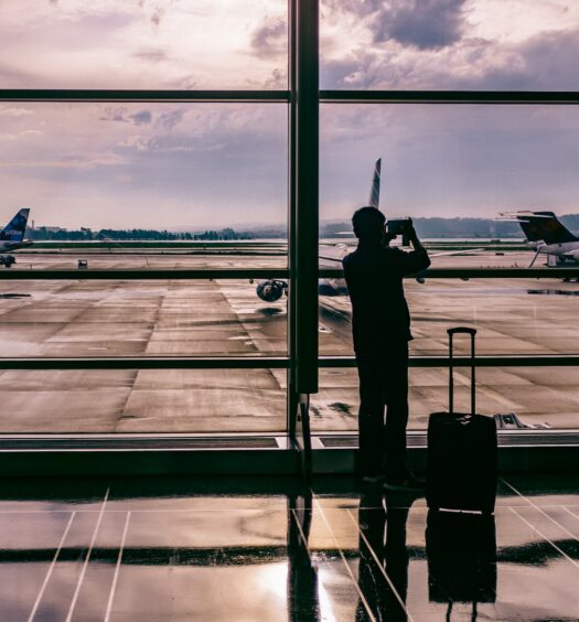 vista do Ronald Reagan Washington National Airport, Arlington ao entardecer com uma pessoa e uma mala segurando um celular em que tira fotos através do vidro de aviões em um espaço aberto